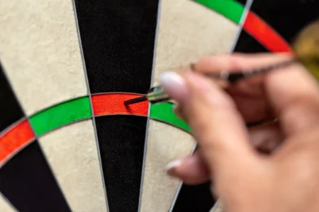 Nahaufnahme, Frau zieht Steeldart aus dem Dartboard, Dartsport bei Damen