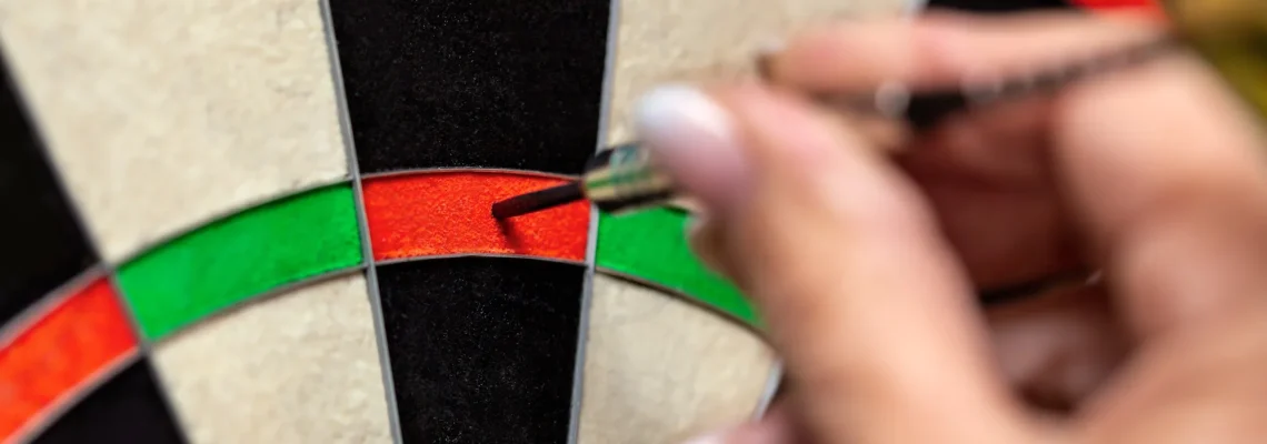 Nahaufnahme, Frau zieht Steeldart aus dem Dartboard, Dartsport bei Damen